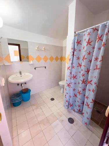 a bathroom with a shower curtain with a sink and a toilet at Villaggio Camping Esca in Marina di Camerota