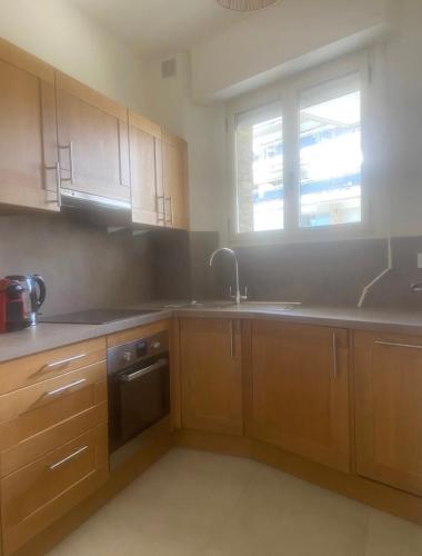 une cuisine avec des armoires en bois, un évier et une fenêtre dans l'établissement palm Beach studio vue port Canto, à Cannes