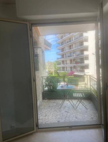 une porte coulissante en verre menant à un balcon avec une table. dans l'établissement palm Beach studio vue port Canto, à Cannes