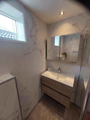 a white bathroom with a sink and a mirror at 't Vakansie'uus in Serooskerke