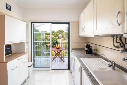 a kitchen with white cabinets and a door leading to a patio at Casa Flandriana in Carvoeiro