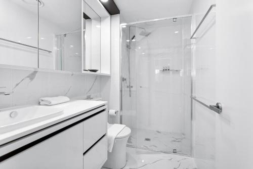 y baño blanco con ducha y aseo. en Central 2-Bed with Gym, BBQ & Stunning Views, en Canberra
