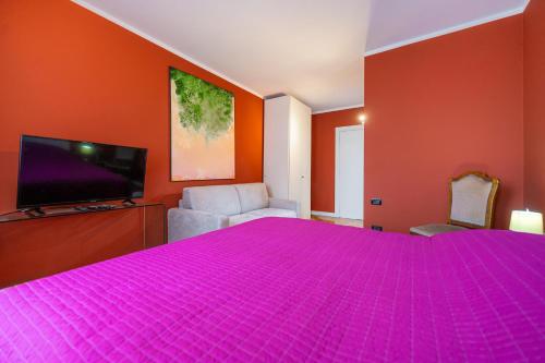 a bedroom with a pink bed and a flat screen tv at B&B Corso Mazzini 22 - Between Verona & Garda Lake in Bussolengo