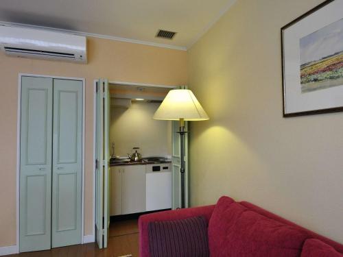 a living room with a red couch and a kitchen at Forest Villa Huis Ten Bosch in Sasebo