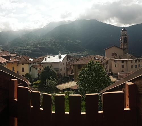 a view of a town with a clock tower and mountains at L'angolo del buonumore in Daone