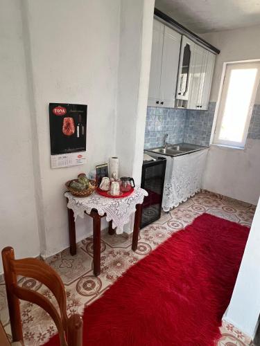 Guest House Leskovik في Leskovik: مطبخ صغير مع طاولة وسجادة حمراء