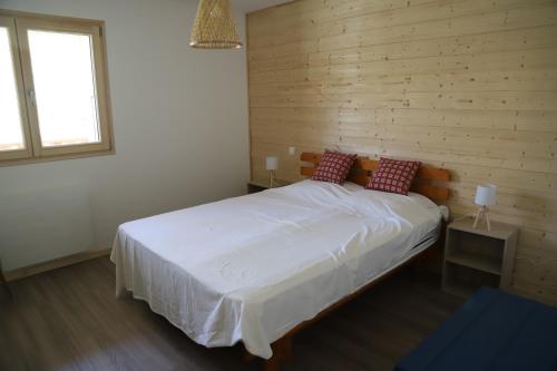 a bedroom with a white bed with a wooden wall at Les Curtillets in Bellevaux