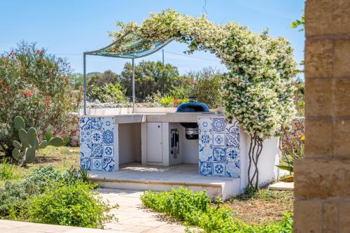 an outdoor kitchen in a garden with a flowering plant at Leukos, dimora di charme in Salve