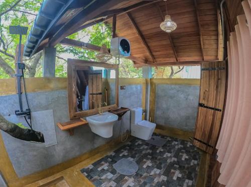 a bathroom with a sink and a toilet and a mirror at Sundown Lake Hotel & Spa in Habarana
