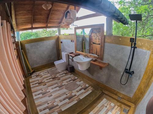 a bathroom with a sink and a toilet and a mirror at Sundown Lake Hotel & Spa in Habarana