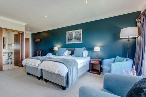 a bedroom with a large bed and a blue wall at Garden Route Ilita Lodge in Groot Brak Rivier
