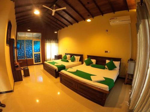 a bedroom with two beds with green pillows at OYO KINGS HOTEL in Katunayake