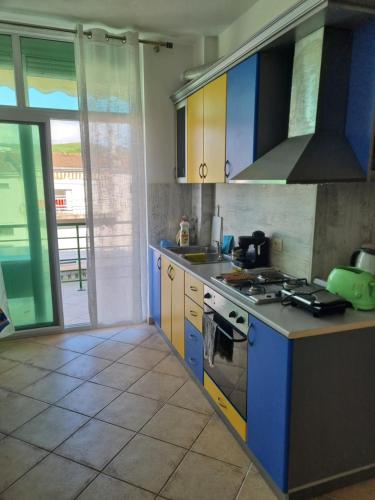 une cuisine avec des armoires bleues et jaunes et une cuisinière dans l'établissement Seashore Serenity Apartment, à Golem