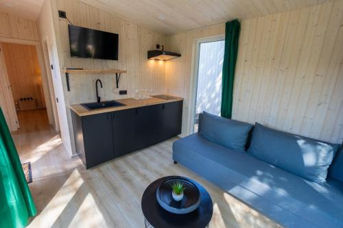 a living room with a blue couch and a kitchen at Baltic Beach Houses & Jomas in Jūrmala