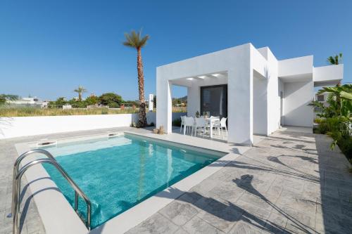a villa with a swimming pool and a dining area at Salty Sun Luxury Villas in Kremasti