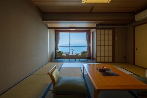 Pokój ze stołem i krzesłami oraz widokiem na ocean w obiekcie Fufurotenburonoyado Ginsyou w mieście Ibusuki