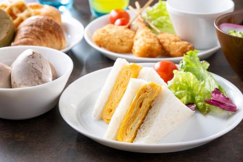 a table with plates of food with sandwiches and salad at Just Sleep Osaka Shinsaibashi in Osaka