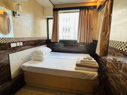 Un pequeño dormitorio con una cama con toallas. en USA Hostel HONG KONG, en Hong Kong