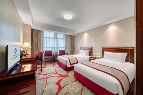 una camera d'albergo con due letti e una scrivania di Hangzhou Haiwaihai Communication Hotel a Hangzhou