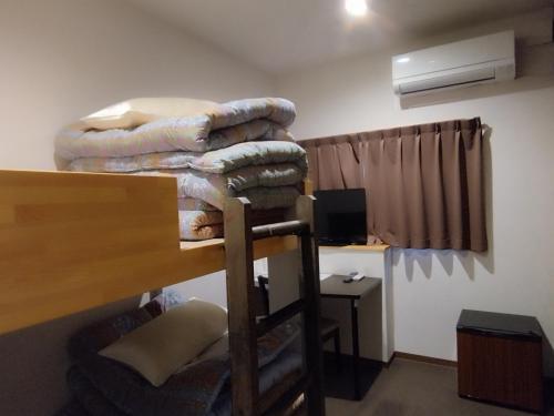 a room with a stack of blankets and a desk at GATE80長居 in Osaka