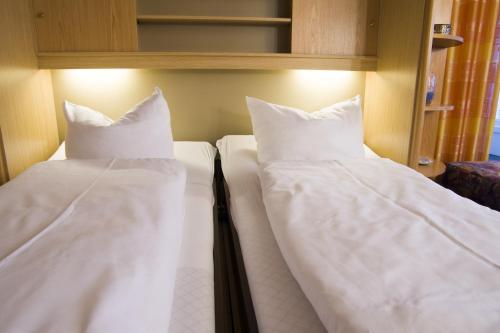 two beds in a room with white sheets and pillows at Frische Brise FeWo 09 08 in Cuxhaven