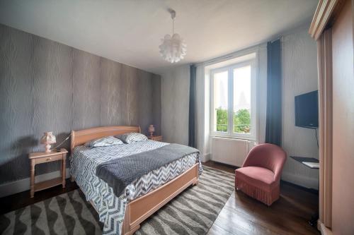 a bedroom with a bed and a chair and a window at Au bord de La Saône - Maison pour 6 avec jardin in Uchizy