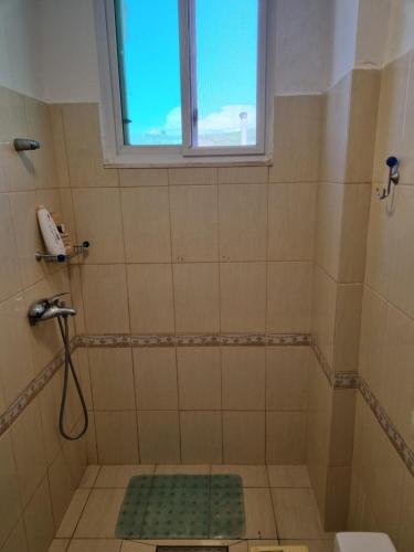 La salle de bains est pourvue d'une douche et d'une fenêtre. dans l'établissement Seashore Serenity Apartment, à Golem
