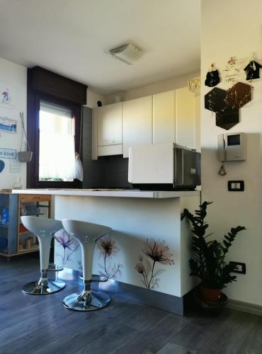 a kitchen with white cabinets and a counter with stools at SunDays House #casa al mare in Quartu SantʼElena