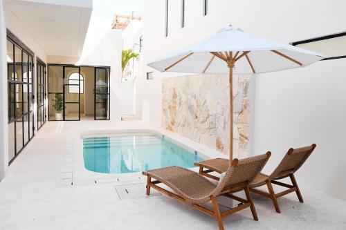 a swimming pool with two chairs and an umbrella at Casa Lily - Luxury 3 Bedroom Villa in Bingin in Uluwatu