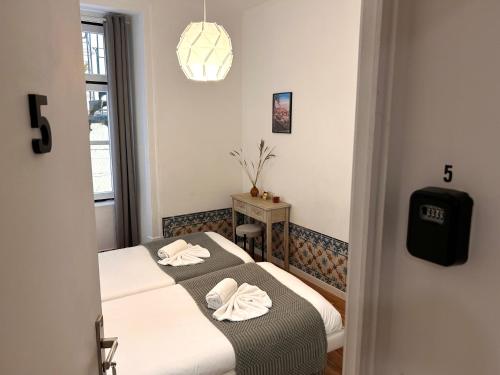 262 Baixa Guesthouse في لشبونة: سريرين في غرفة صغيرة مع نافذة