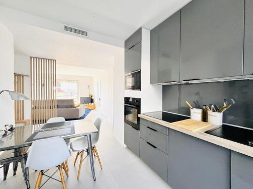 une cuisine avec des armoires grises et une table et des chaises dans l'établissement L'impérator - Petit Juas Cannes, à Cannes