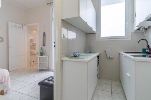 une cuisine avec des armoires blanches, un évier et une fenêtre dans l'établissement Arca Day - Appt 4p à Arcachon proche dune du pilat, à Arcachon