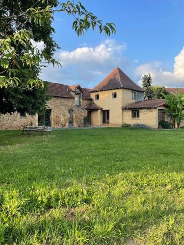 an old stone building with a bench in a field at Grande maison type Périgourdine in Montignac