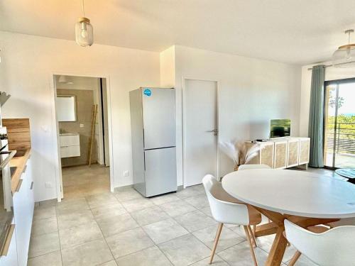 une cuisine et une salle à manger avec une table et un réfrigérateur dans l'établissement Appartement Tour d'Omigna Cargèse, à Cargèse