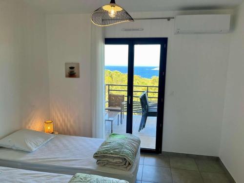 a bedroom with a bed and a view of a balcony at Appartement Tour d'Omigna Cargèse in Cargèse