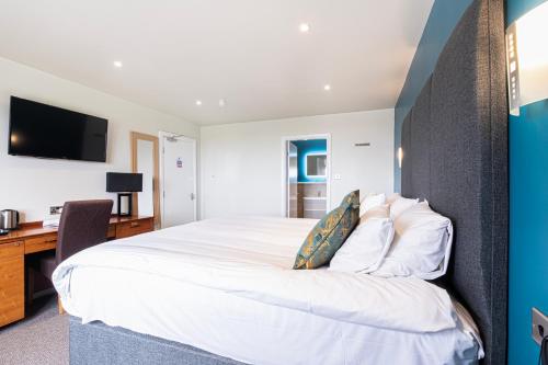 a bedroom with a large white bed and a desk at Springfield Hotel & Health Club in Halkyn