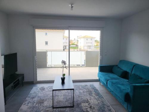 un soggiorno con un divano blu e un tavolo di New villa 5mn from the beach-Pyrenees view a Sainte-Marie-la-Mer