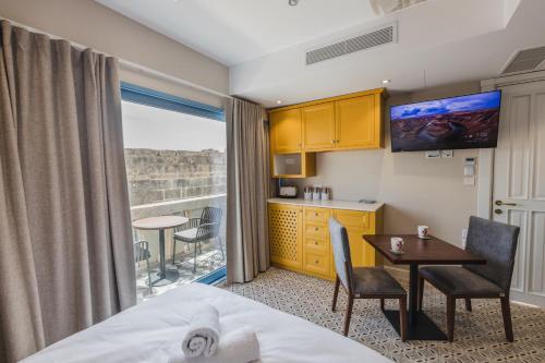 a hotel room with a bed and a table and a kitchen at IŻ-ŻEBBUĠA BOUTIQUE SUITES in Żebbuġ