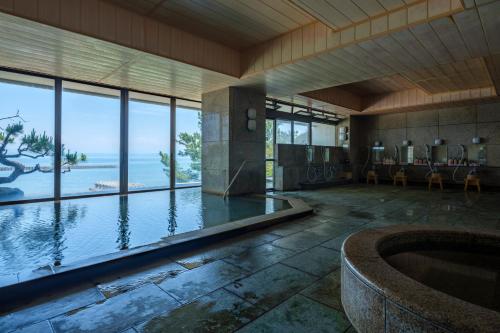 a room with a swimming pool with a view of the ocean at Fufurotenburonoyado Ginsyou in Ibusuki