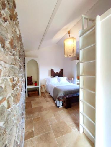 une chambre avec un lit et un mur en pierre dans l'établissement L'Atelier des Huppes, à Joyeuse