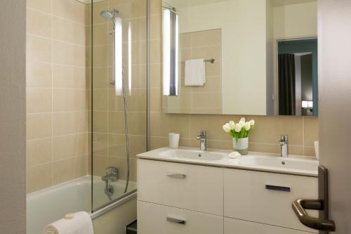 La salle de bains est pourvue d'un lavabo, d'un miroir et d'une baignoire. dans l'établissement Citadines Antigone Montpellier, à Montpellier