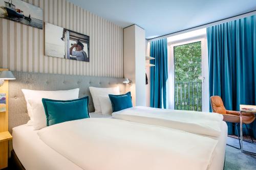 a hotel room with two beds and a window at Motel One Rostock in Rostock