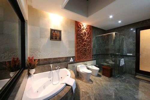 a bathroom with a tub and a toilet and a shower at PURI BALI STANIA, Cisarua West Java in Cilama