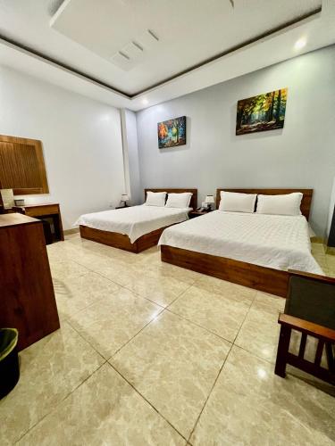 two beds in a large room with two bedsvisor at Khách Sạn Trung Anh 78 HAI BÀ TRƯNG BMT in Buon Ma Thuot
