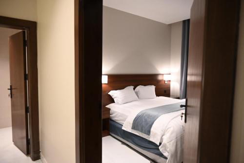 a bedroom with a bed and a door to a room at شقق اناسي الوردية للشقق المخدومة in Al Baha