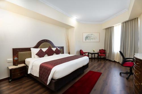 een hotelkamer met een groot bed en een rood tapijt bij Hotel Presidency in Cochin