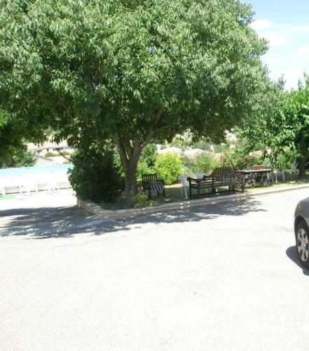 un groupe de bancs de parc sous un arbre dans l'établissement Meublé14 avec terrasse, à Gréoux-les-Bains