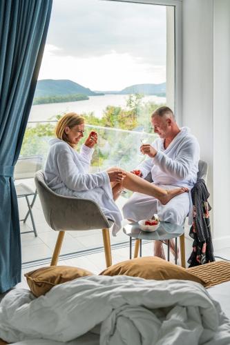 a man and a woman sitting in a room with drinks at Akvarell Apartmanház in Zebegény