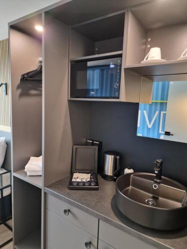 eine Küche mit einer Spüle und einer Mikrowelle in der Unterkunft Pro Messe Hotel Hannover in Hannover