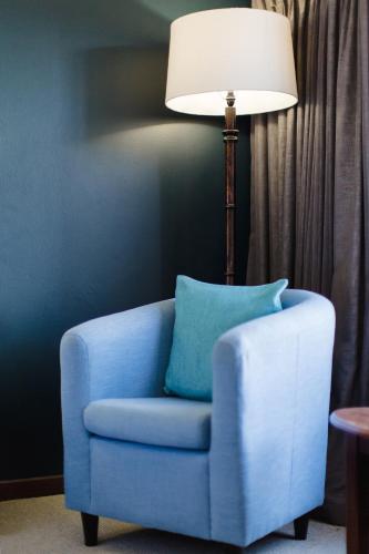 a blue chair with a lamp in a room at Garden Route Ilita Lodge in Groot Brak Rivier